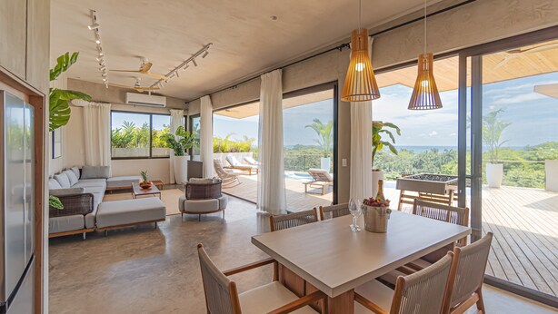 A spacious living area with a large dining table, comfortable seating, and a view of the outdoors. - Blanco Mar Ocean view (Cóbano)