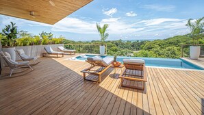 A wooden deck with lounge chairs and a pool, overlooking a lush landscape. - Blanco Mar Ocean view (Cóbano)