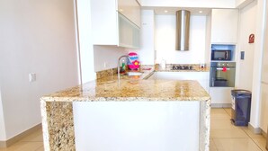 A modern kitchen with a granite countertop, stainless steel appliances, and a built-in oven. - Your Perfect Getaway! Daily Rental in Apartment H2 2305 Seafront (Cartagena)