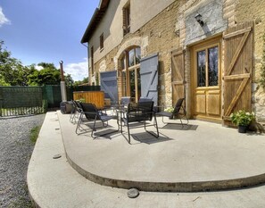 Traditional European-style building with a charming exterior, featuring a porch and patio area with outdoor seating.