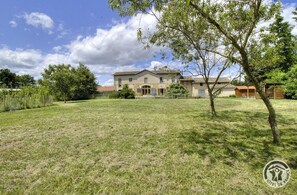 Stunning two-story building with a traditional facade, set amidst a serene and lawn surrounded by mature trees.