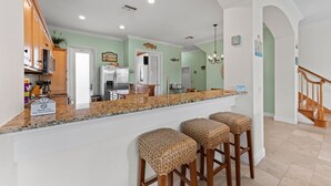 A kitchen with a granite countertop, wooden stools, and a 'Thank You For Not Smoking' sign. - Sunset Views Bradenton Unit A (Bradenton Beach)
