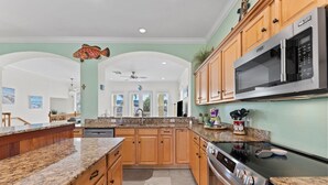 A kitchen with granite countertops, wooden cabinets, a stainless steel stove, and a microwave. - Sunset Views Bradenton Unit A (Bradenton Beach)