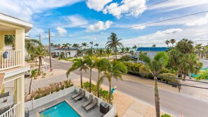 A residential area with a swimming pool, palm trees, and a road. - Sunset Views Bradenton Unit A (Bradenton Beach)