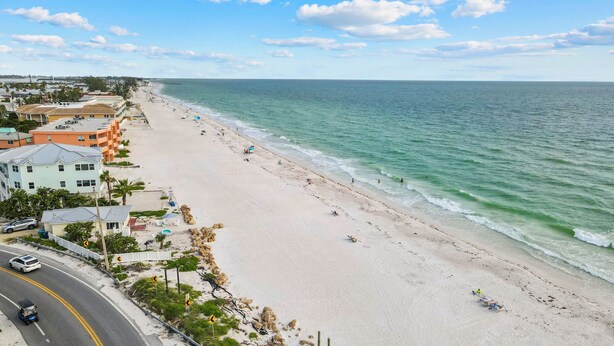 Une plage bordée d’une route qui la longe, des immeubles dotés de balcons et une vue dégagée sur l’océan.