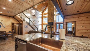 A spacious kitchen with granite countertops, a large sink, and a wooden interior.