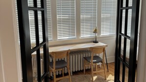 Une pièce avec un bureau en bois, deux chaises, un radiateur et un tapis moelleux.