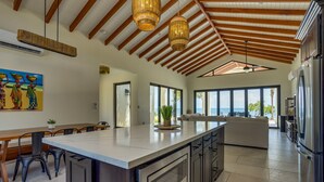 Une cuisine spacieuse dotée d’un grand îlot central, d’appareils électroménagers modernes et de grandes fenêtres offrant une vue sur l’extérieur.