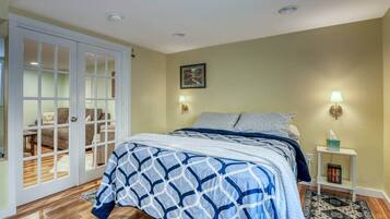 Une chambre à coucher comprenant un lit, une table de chevet, une lampe, un tableau au mur et une porte coulissante donnant sur un espace de vie.