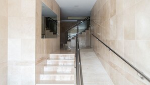 Et moderne interiør med en marmortrappe, glasgelændere og et rent, minimalistisk design.