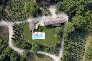 An aerial view of a property with a swimming pool, a large house with a tiled roof, and surrounding greenery. - Villa San Vicenzo By MMega (Umbertide)