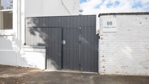 A gated entrance with a white brick wall and a sign indicating the address as 98 Prestbury Road. - Large Period 2-Bed Apartment Close to Town (Gloucestershire)