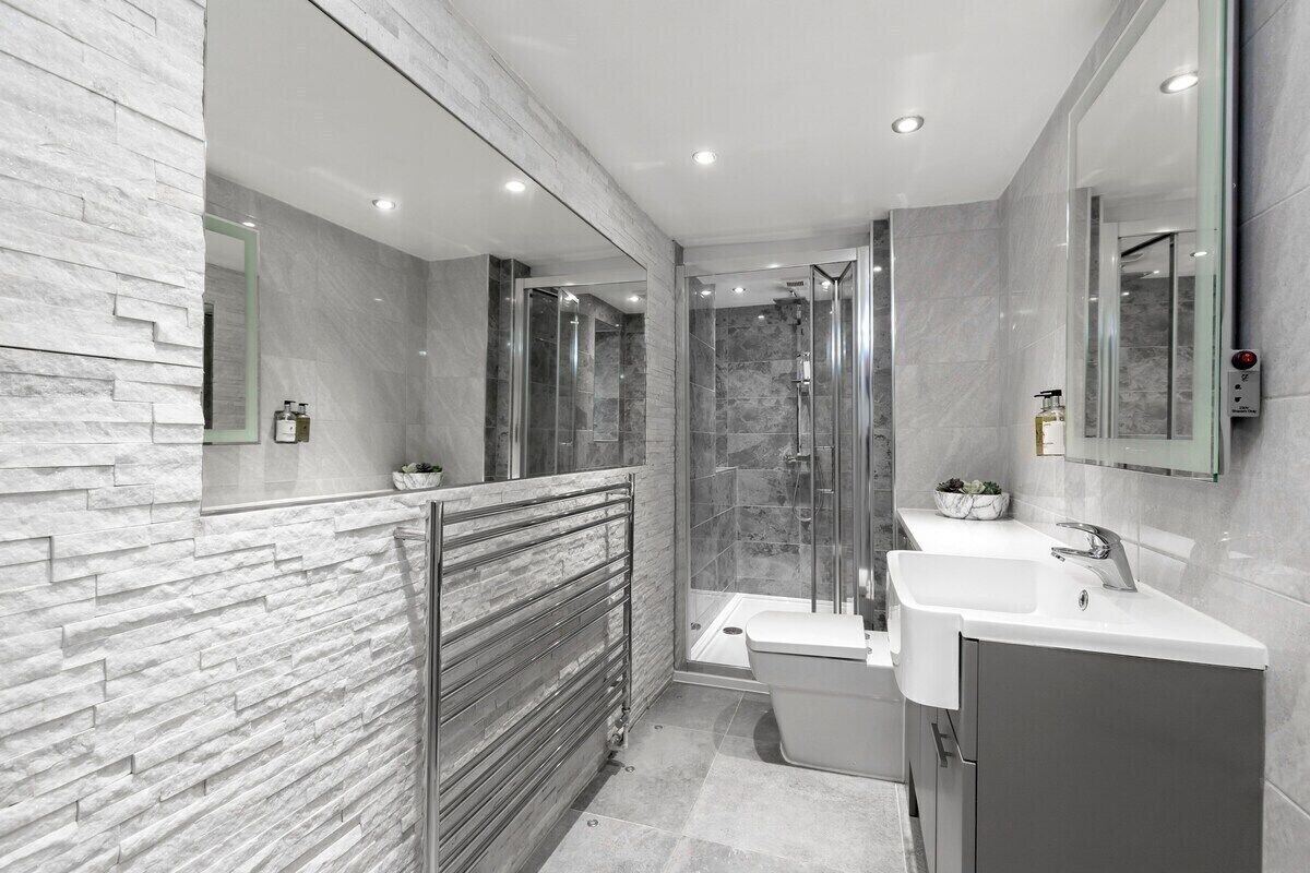 A modern bathroom with a glass shower enclosure, a standalone bathtub, and a vanity with a sink and mirror.