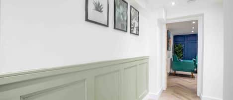 A hallway with a green wainscoting, a white wall, and three framed botanical prints.