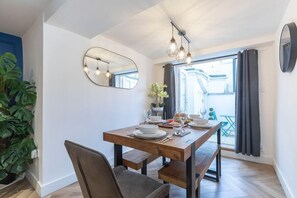 Un comedor con una mesa de madera, sillas y un espejo en la pared.