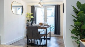 A dining area with a wooden table, chairs, and a hanging light fixture. - Large Period 2-Bed Apartment Close to Town (Gloucestershire)