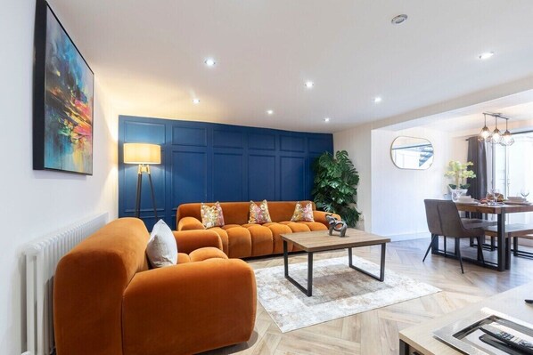 A modern living room with a sofa, a coffee table, and a dining area with a table and chairs.