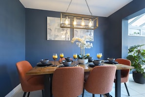 A dining area with a wooden table, orange chairs, and a modern pendant light.