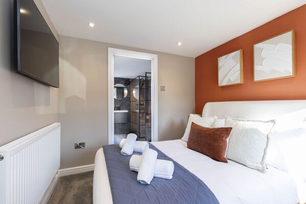 Una habitación de hotel moderna con una cama grande, un televisor de pantalla plana y obras de arte en las paredes.