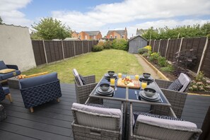 Una terraza con mobiliario exterior y una mesa de comedor dispuesta para una comida.