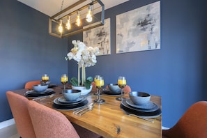 Comedor con mesa de madera dispuesta para cuatro personas, rodeado de sillas color naranja.
