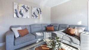 Una sala de estar moderna con un sofá modular gris, arte abstracto en la pared y una mesita de centro con una planta.
