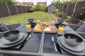 Une table dressée pour le petit-déjeuner, avec des assiettes, des bols, des couverts et un plateau de fruits et de fromage.