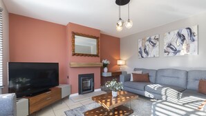 Una sala moderna con una televisión de pantalla plana, chimenea, sofá y arte abstracto en la pared.