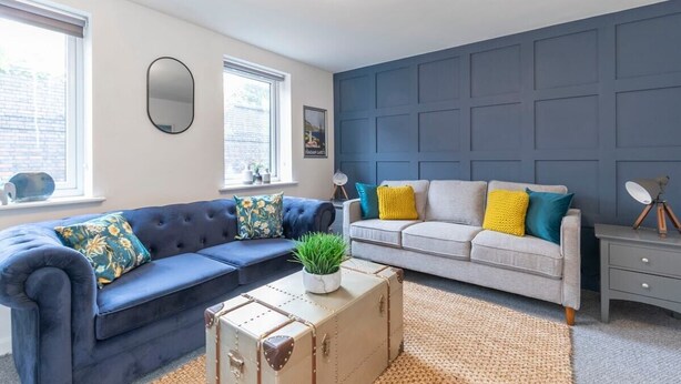 Ein Wohnzimmer mit zwei Sofas, einem Couchtisch, einem Spiegel und einer Kommode.
