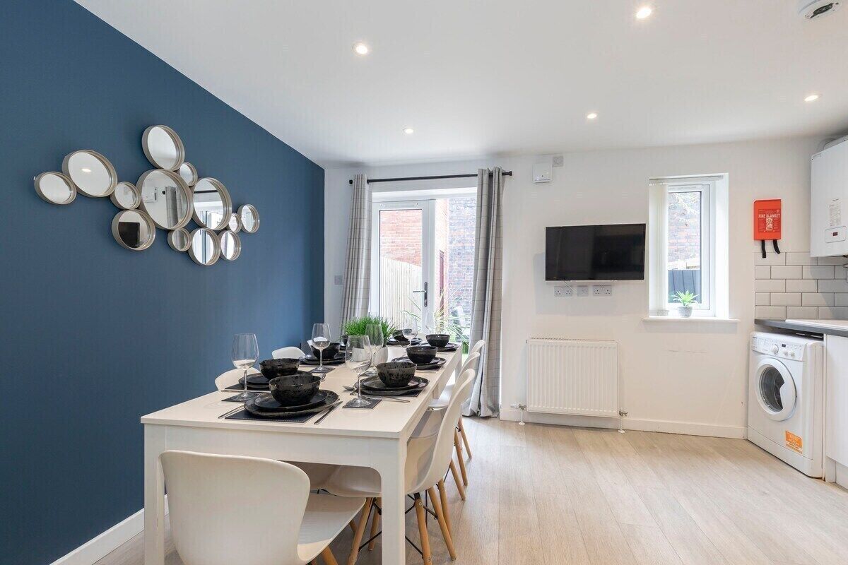 A modern kitchen with a dining area, a washing machine, and a TV.