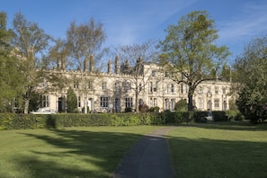 A large, historic building with a symmetrical facade, surrounded by well-maintained lawns and trees.