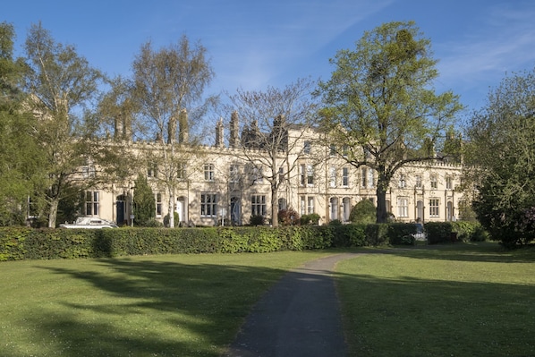A large, historic building with a symmetrical facade, surrounded by well-maintained lawns and trees.