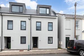 A modern two-story residential building with a flat roof, multiple windows, and a black van parked in front. - Modern 4 Bedroom 4 Bathroom Home in Cheltenham (Cheltenham)