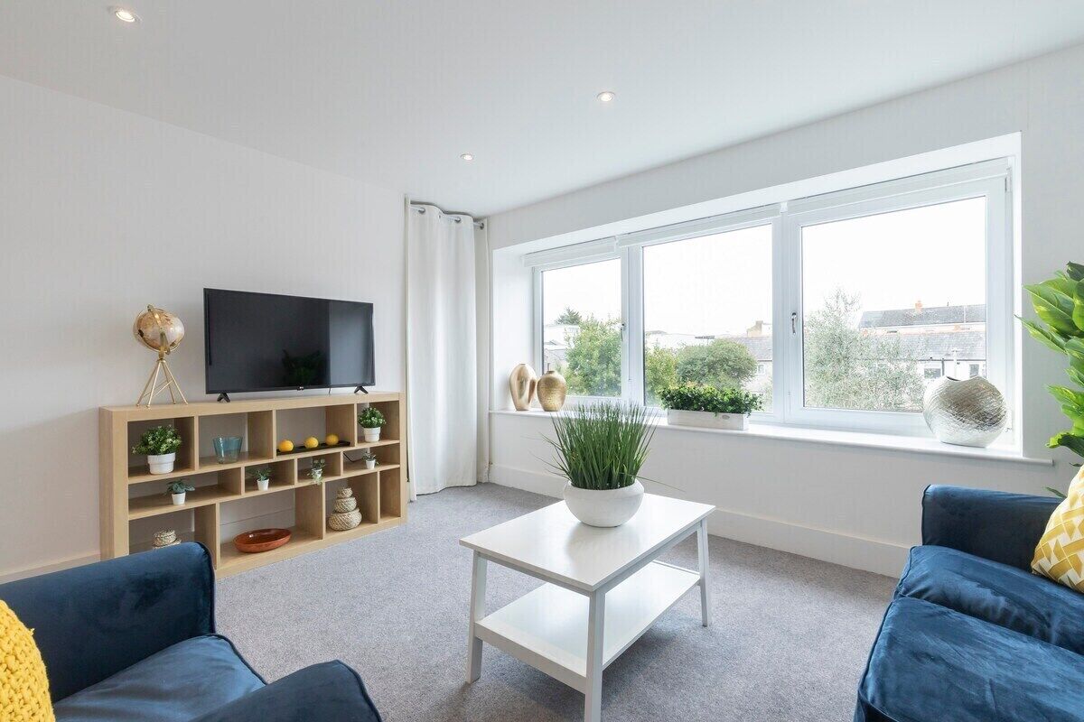 A modern living room with a flat-screen TV, a white coffee table, and a blue sofa.