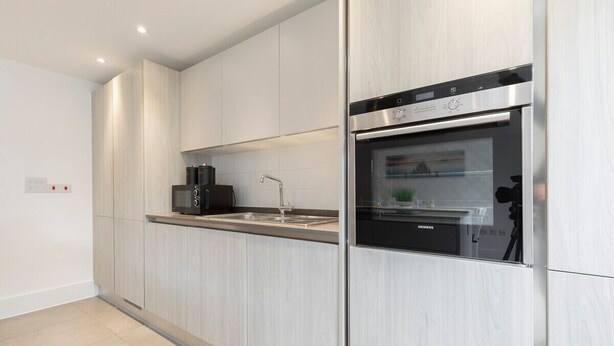 A modern kitchen with stainless steel appliances, a built-in oven, and a microwave. - Modern & Spacious Home in Central Cheltenham (Gloucestershire)