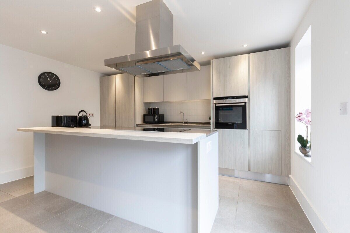A modern kitchen with a central island, stainless steel appliances, and light wood cabinetry.
