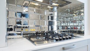 A modern kitchen with a stainless steel stove, a marble backsplash, and a glass-fronted storage area. - Stunning 5 Bed Regency Home (Gloucestershire)