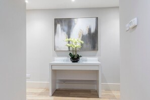 A modern, minimalist room with a white console table, a large abstract painting, and a potted orchid.