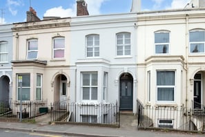 A row of white terraced houses with uniform architectural style, featuring bay windows and a symmetrical facade.