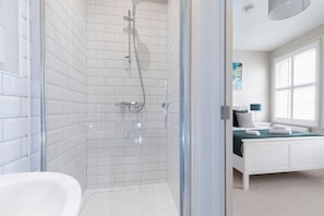 A modern bathroom with white subway tiles, a glass-enclosed shower, and a white bathtub.