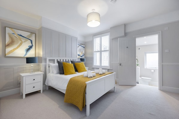 A bedroom with a bed, bedside tables, a nightstand, a window, and a door.