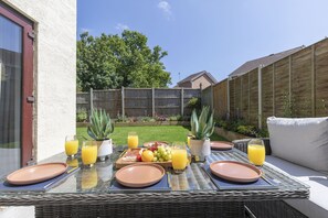 Eine Terrassenanlage im Freien mit einem Frühstückstisch, komplett mit Tellern, Orangensaftgläsern und einer Obstplatte.