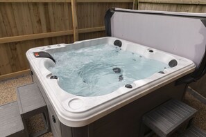 A hot tub with a wooden deck and steps leading into it.
