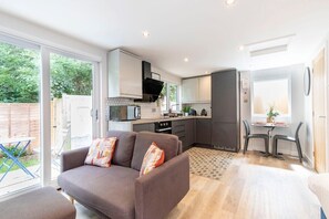 A modern kitchen with a dining area, a sofa with cushions, and a view of the outdoors.