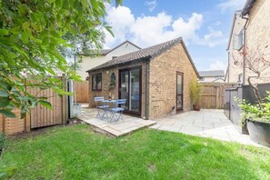 A brick house with a patio, a wooden fence, and a small garden area.