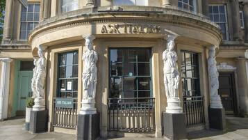 A building with classical architecture, featuring columns and statues around the entrance.