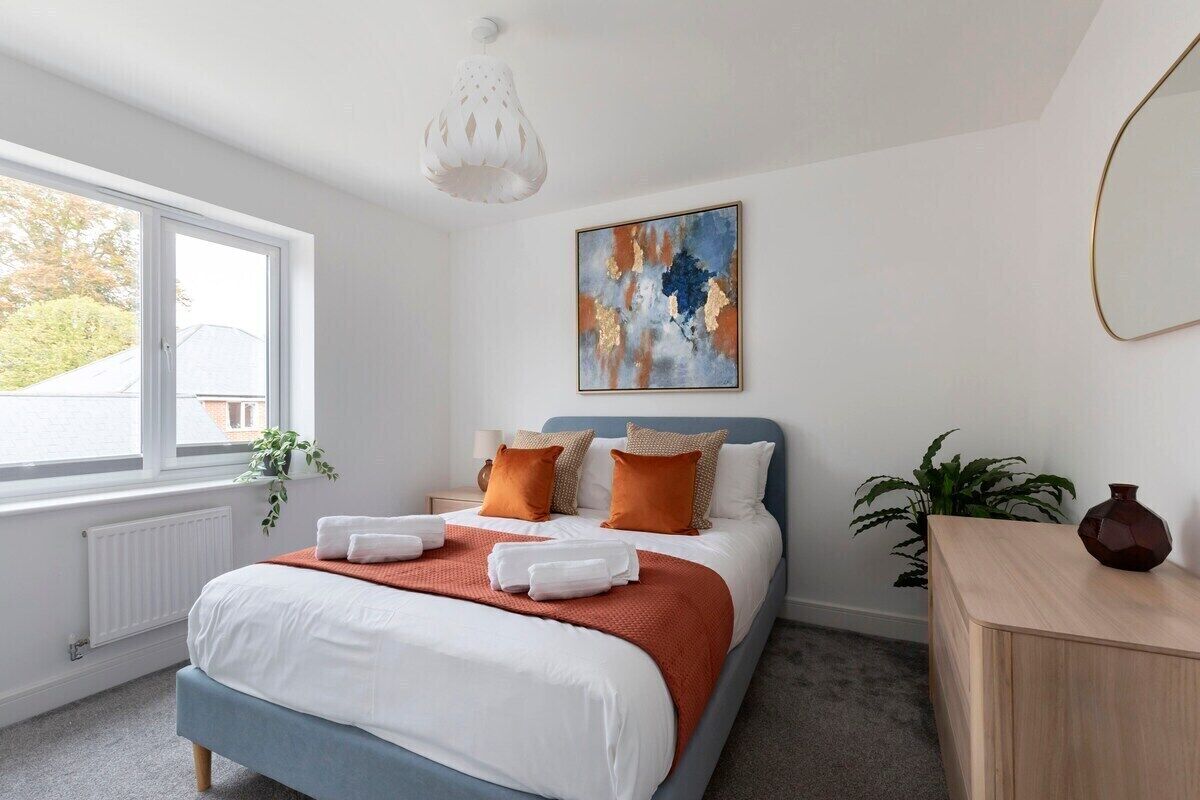 Une chambre à coucher avec un lit, une fenêtre, un tableau et une plante.