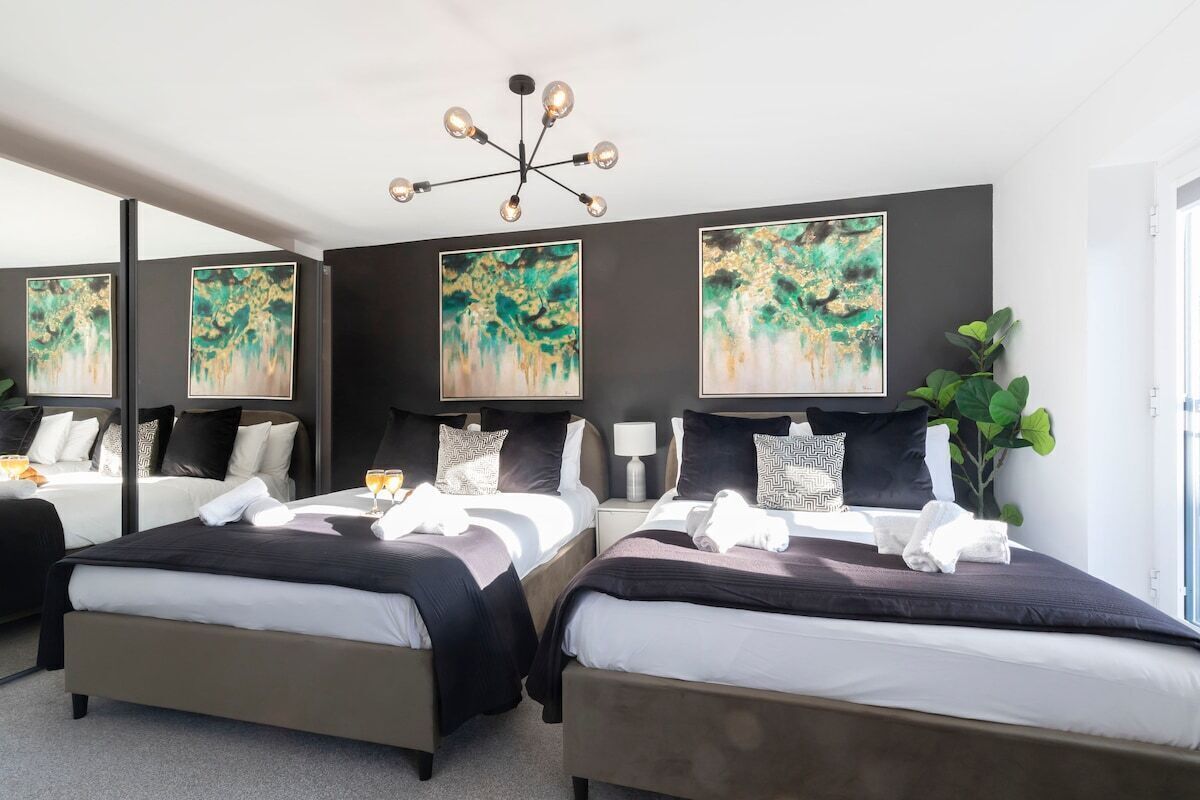Ein Hotelzimmer mit zwei Betten, einer modernen Kronleuchter und abstrakten Bildern an den Wänden.