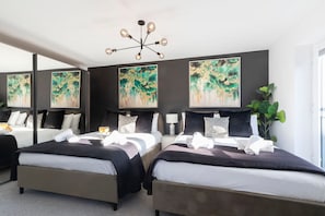 Una habitació d'hotel amb dos llits, una làmpada de cristall moderna i quadres abstractes a les parets.