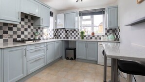 A kitchen with light blue cabinets, a checkered backsplash, and a window with a view of buildings outside.